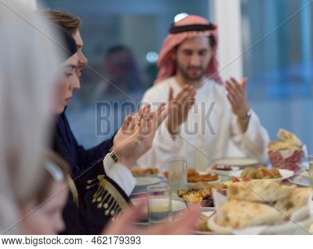 Muslim family making iftar dua to break fasting during Ramadan.