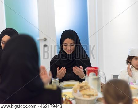 Muslim family making iftar dua to break fasting during Ramadan.