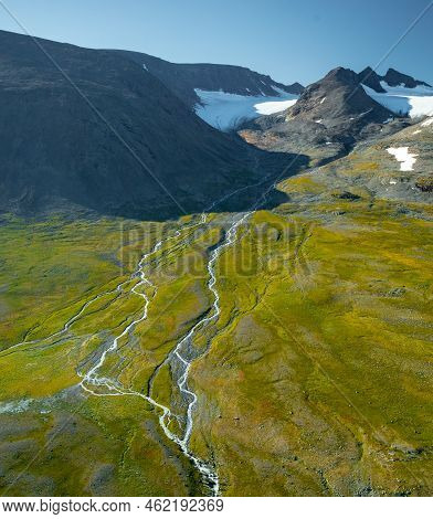 Wild River Flowing From Mountain Glaciers In Vast Remote Arctic Landscape. Ahpartjahkka Mountain In 