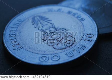 Translation: 10 Baht Thailand. Thai Coin Of 10 Baht Closeup. Dark Blue Tinted Background. News About