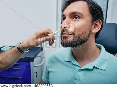 Adult Man During Rhinoscopy In Ent Office. Doctor Using Nasal Speculum Or Rhinoscope To Examine Pati