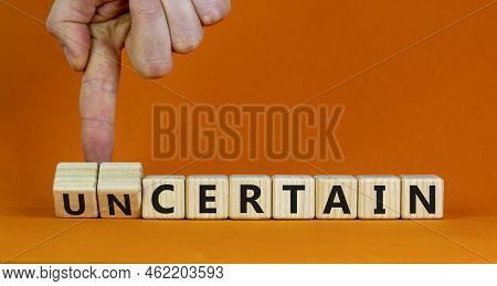 Certain Or Uncertain Symbol. Businessman Turns Wooden Cubes And Changes The Concept Word Uncertain T