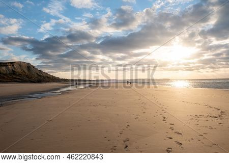 Sandy Beach At The Sea Under A Sky Painted With Clouds And A Golden Sun, Showing An Amazing Colorful