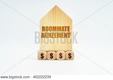 Real Estate And Business. On A White Surface Stands A Wooden Model Of A House With The Inscription -