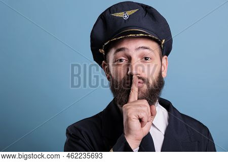 Airplane Pilot Showing Silent Gesture, Looking At Camera With Forefinger On Lips. Aviation Academy P