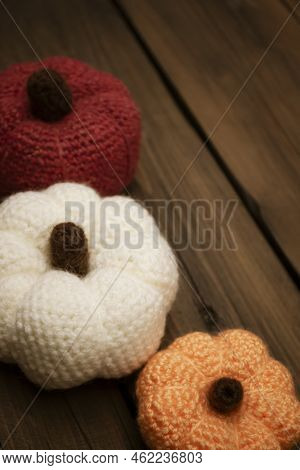 Three Pumpkins Crocheted Stand On A Wooden Table. Autumn Decorations For Halloween. On A Wooden Tabl