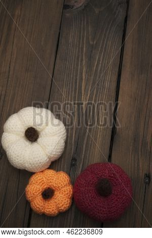 Three Pumpkins Crocheted Stand On A Wooden Table. View From Above. Orange. White And Red Yarn Tyva, 