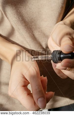 Close-up Of Pipette With Collagen Moisturizing Hyaluronic Serum In Woman's Hand. Liquid Drips From D