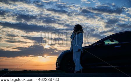 Beautiful Sunset. Silhouette Of Girl Standing On Road, Enjoying Incredible Sunset Over Horizon At Cl