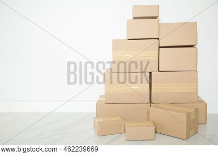Stack Of Cardboard Boxes For Moving, Empty Room With A White Wall And Cardboard Boxes With Unbranded