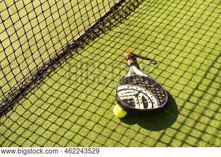 Yellow Balls On Grass Turf Near Padel Tennis Racket Behind Net In Green Court Outdoors With Natural 