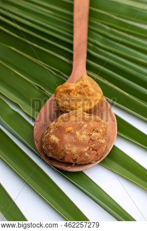 Closeup Of Organic Palm Jaggery Or India Gur In A Wooden Ladle On Isolated On Palm Leaf In Vertical 