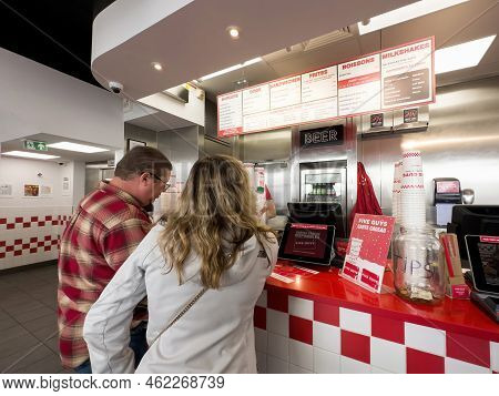 Paris, France - Sep 21, 2022: Customers At The Counter Reading The Menu Above Five Guys American Fas