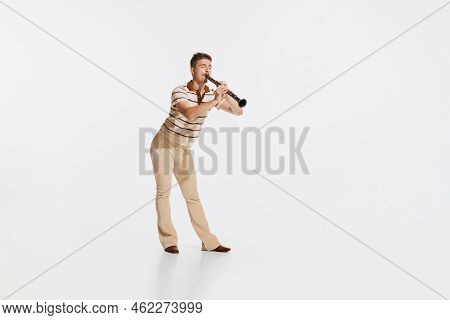 Young Man Wearing 50s, 60s Fashion Style Clothes Playing Clarinet On White Studio Backround. Music, 