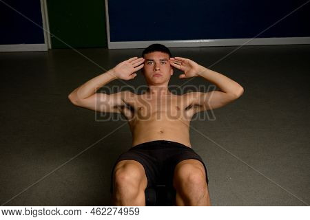 Shirtless 19 Year Old Teenage Boy Soing Situps On An Exercise Bench