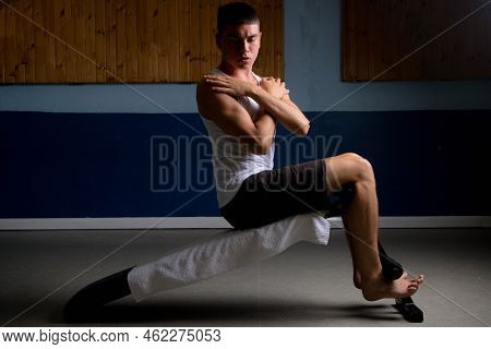 19 Year Old Teenage Boy Doing Situps On An Excercise Bench In A Tank Top
