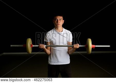 19 Year Old Teenage Boy Excercising His Biceps With A Barbell