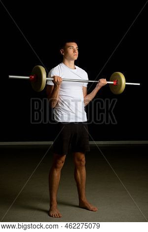 19 Year Old Teenage Boy Excercising His Biceps With A Barbell