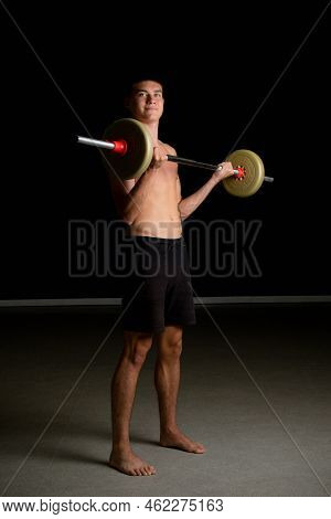 Shirtless 19 Year Old Teenage Boy Excercsing His Bicpes With A Barbell