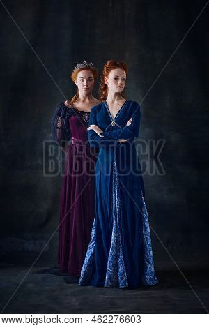 Portrait Of Two Beautiful Women In Image Of Queens Isolated Over Dark Background. Royal Family Portr