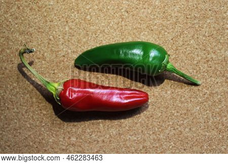 Red And Green Chili Peppers On Table. Photo Of Two Chili Pepper On A Cork Background