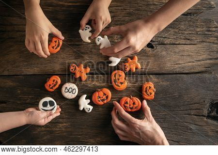 Children's Hands Reach For Halloween Holiday Gingerbread In The Form Of Ghosts, Pumpkins And A Ginge