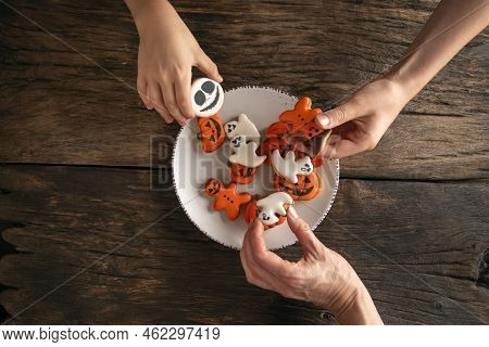 Halloween Pumpkin, Ghosts And Ginger Man.hands Reach For Handmade Edible Gingerbread On Plate. Top V