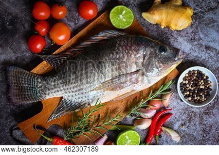 Tilapia With Spice Rosemary Tomato Lemon Lime Ginger Garlic Pepper Chili On Dark Background, Fresh R