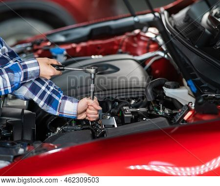 Female Auto Mechanic Unscrewing A Nut To Replace A Car Spark Plug.