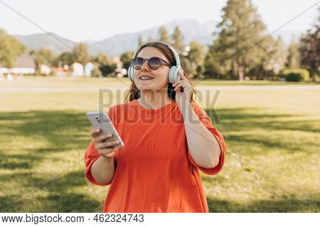 Close Up Portrait Of A Lovely Happy Young Woman In Sunglasses Listening To Music Through Wireless Ea
