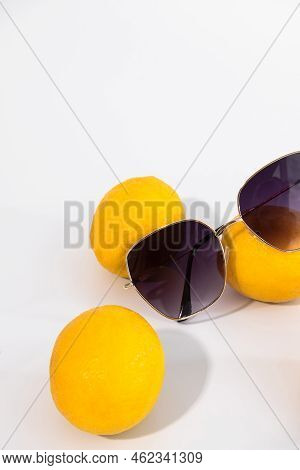 Sunglasses lying on yellow juicy lemons. High quality photo