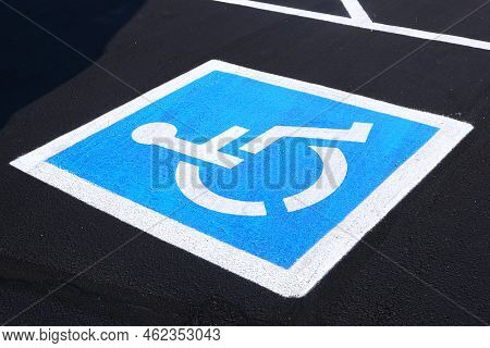 Disabled Parking Space With White And Blue Painted Sign Of Handicapped Parking Spot On Blacktop Asph