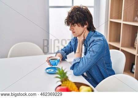Young hispanic man dtinking coffee suffering for throat pain at home
