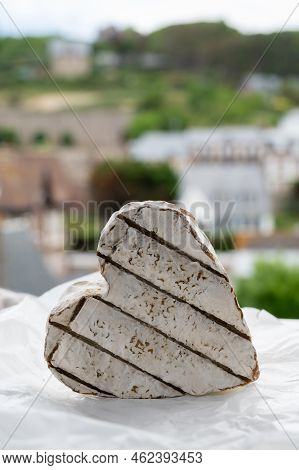 French Heartshaped Neufchatel Cow Cheese On White Paper And View On Old Houses Of Etretat, Normandy,