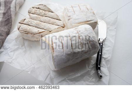 French Cheeses Heartshaped, Squared And Cylindrical Neufchatel Cow Cheese With Mold On White Paper,