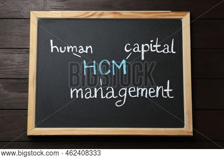 Small Blackboard With Abbreviation Hcm (human Capital Management) On Wooden Background, Top View