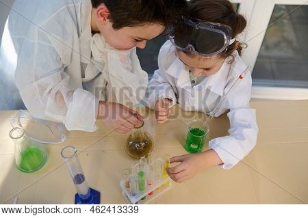Overhead View Of Smart School Kids, Wearing White Lab Coat, Learning Chemistry In The School Science