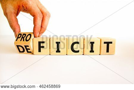 Proficit Or Deficit Symbol. Businessman Turns Wooden Cubes And Changes The Concept Word Deficit To P