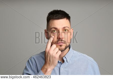Man Checking His Health Condition On Grey Background. Yellow Eyes As Symptom Of Problems With Liver