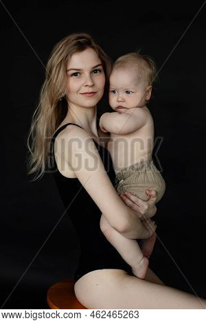 Vertical Portrait Of Young Attractive Fair Haired Woman Carrying Adorable Shy Baby In Diapie, Embrac