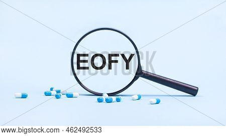 On A Blue Background, White And Blue Capsules With Pills And A Black Magnifying Glass With The Text 