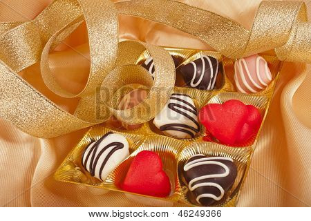 cuori di cioccolato e marchpane caramelle su sfondo dorato stoffa di seta con texture