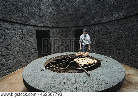 Cook Grilling Chicken On Volcanic Heat In El Diablo Restaurant, Spain