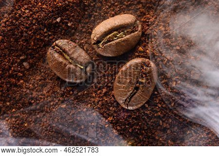 Ground Coffee And Three Beans In A Light Smoke.