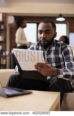 African American Businessman Doing Paperwork In Company Office, Analyzing Data On Documets And Lapto