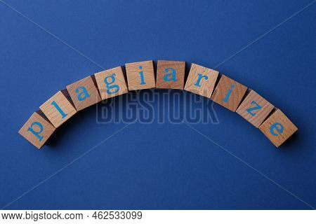 Word Plagiarize Made Of Wooden Cubes With Letters On Blue Background, Top View