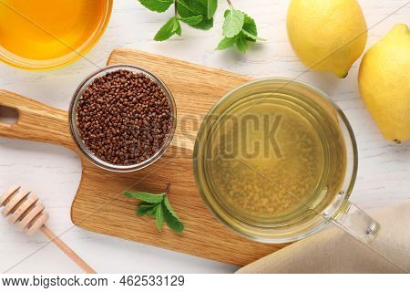 Cup Of Aromatic Buckwheat Tea, Granules, Lemons, Mint And Honey On White Wooden Table, Flat Lay