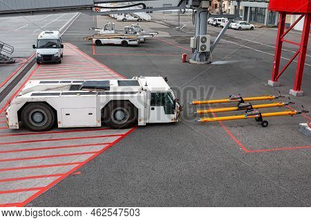 Aircraft Tow Tractor Near Towbars, Self-propelled Conveyor Belt Loaders And Minibus At The Airport A