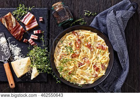 Capunti Pasta In Cream Pecorino Cheese And Pancetta Sauce On Skillet On Dark Wooden Table With Ingre