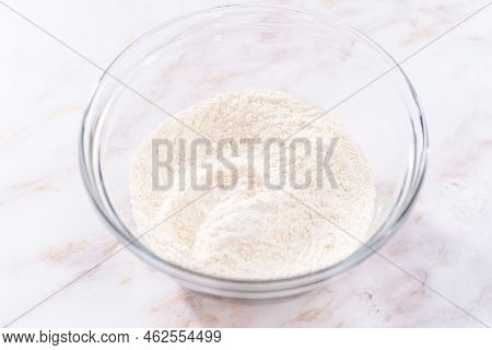 Mixing Ingredients In A Large Glass Mixing Bowl To Bake Apple Sharlotka Muffin.